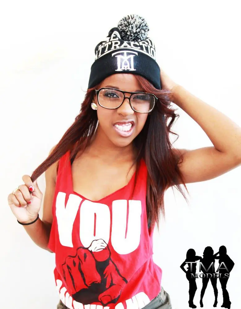 A woman wearing glasses and a hat with the words " you " on it.